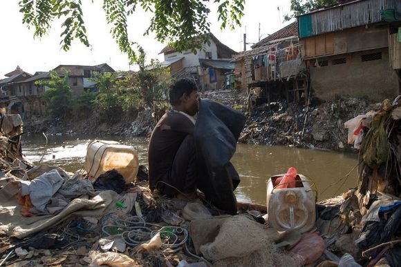 A garbage collector inflates his truck tyre inner-tube. He uses this inflatable raft to drift in the river while he fishes out items from the water ciliwung10.jpg